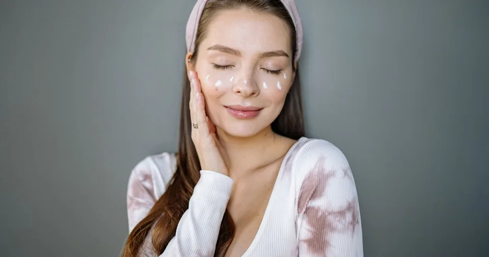 Žena si pri rannej starostlivosti nanáša krém na tvár v malých bodkách