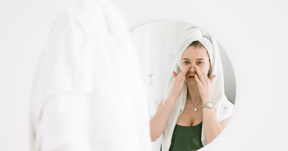 Žena si končekmi prstov jemne vtláča vodové tonikum do pleti pred kúpeľňovým zrkadlom